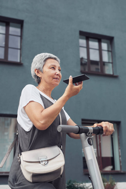 Trendy Mature Woman Using Smartphone in City - Фото, изображение