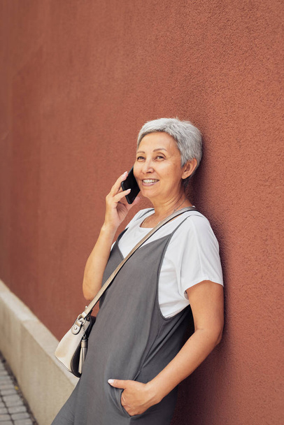Glückliche ältere Frau nutzt Smartphone in der Stadt - Foto, Bild