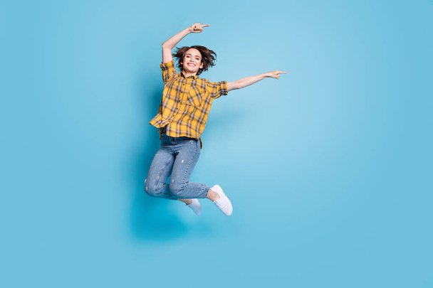 Photo of reliable lady jump direct finger empty space wear plaid shirt jeans shoes isolated blue color background - Φωτογραφία, εικόνα