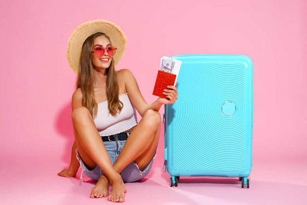 Woman tourist, traveler with passport and tickets, suitcase, white top, shorts, straw hat. - 写真・画像