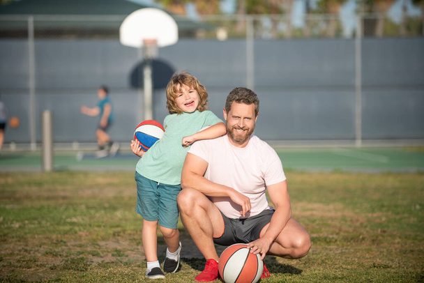 Apa és a kisfiú tartják a sportlabdát. A gyerek kosarazik. gyermekkor és apaság - Fotó, kép