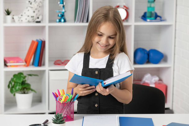 glückliches Kind liest Buch in der Schulstunde im Klassenzimmer tragen Uniform, Leser - Foto, Bild