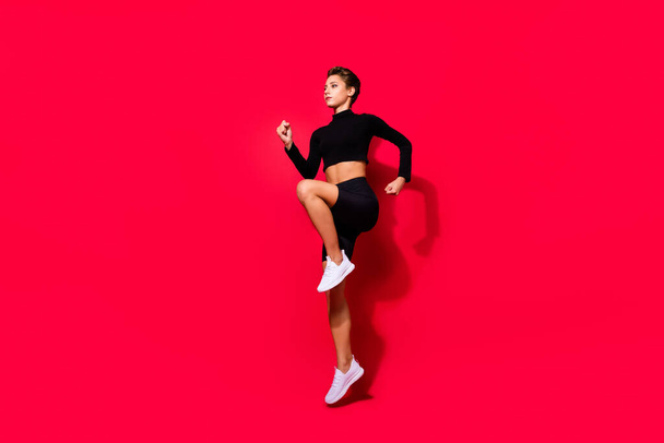 Profile photo of runner serious lady jogging training wear black cropped top isolated red color background - Zdjęcie, obraz