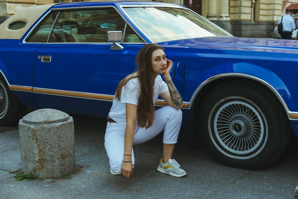 Beautiful girl with long hair on the background of a blue car - Fotoğraf, Görsel