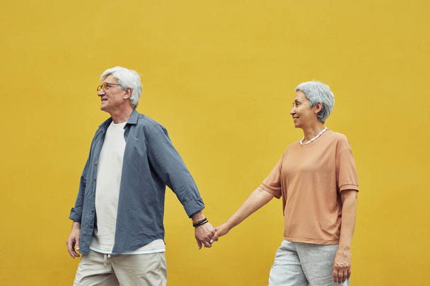 Starší pár drží ruce na žluté - Fotografie, Obrázek