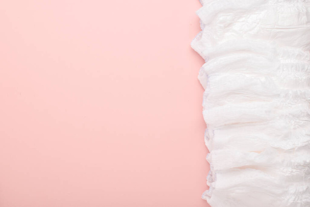 A large stack of disposable diaper panties on a pink background with a place to copy. Flat layout, top view - Foto, afbeelding
