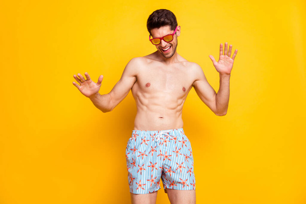 Photo of funny brunet young man dance wear shorts eyewear isolated on yellow color background - Foto, Bild