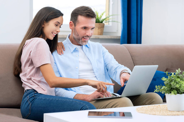 Couple using laptop, watching movie, browsing internet. Surprised man pointing to screen - Foto, Imagem