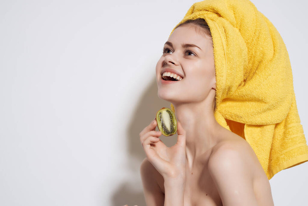 mujer bonita con toalla amarilla en su cabeza desnuda kiwi fruta - Foto, Imagen