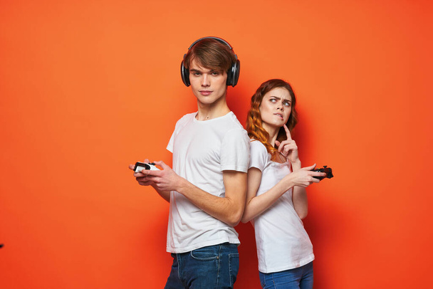 молодая пара в белых футболках с джойстиками в руках, играющая в развлечения - Фото, изображение