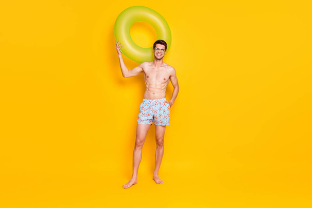 Photo of excited attractive young guy shirtless dark glasses smiling holding water circle isolated yellow color background - Fotó, kép
