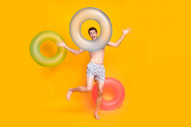 Full body photo of funny brunet millennial guy with buoy wear eyewear shorts isolated on yellow background - Φωτογραφία, εικόνα