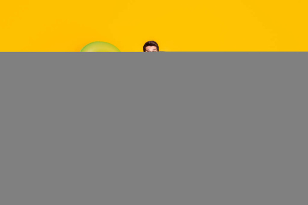 Photo of impressed sweet young guy shirtless dressed dark glasses hands arms sides isolated yellow color background - Foto, afbeelding