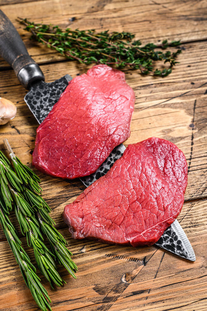 Zwarte angus rauw rundvlees sirloin steak op slagersmes. houten achtergrond. Bovenaanzicht - Foto, afbeelding