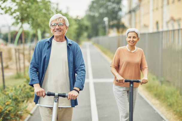 Mature Couple Riding Electric Scooters - Photo, Image