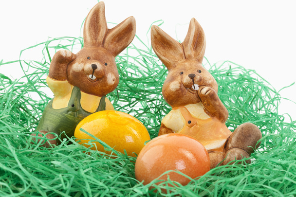 Два пасхальных кролика сидят в гнезде с яйцами
 - Фото, изображение