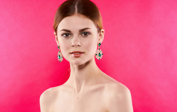 aantrekkelijke vrouw oorbellen kale schouders decoratie Glamor roze achtergrond - Foto, afbeelding