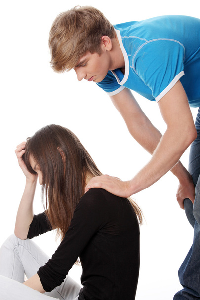 Troubled young girl comforted by her boyfriend. Isolated on white background. - Фото, зображення