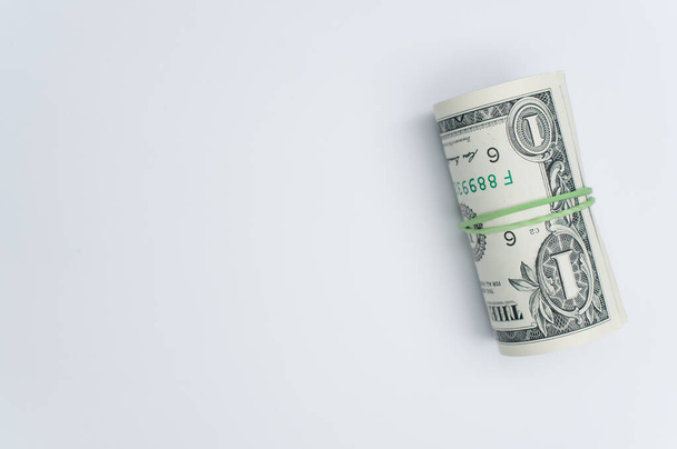 A closeup of a roll of money on light gray background. - Zdjęcie, obraz
