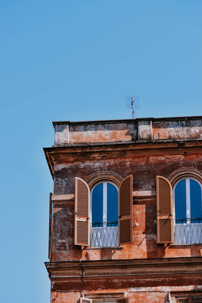 A vertical shot of arched windows with wooden shutters of an old residential building in Rome - Fotografie, Obrázek