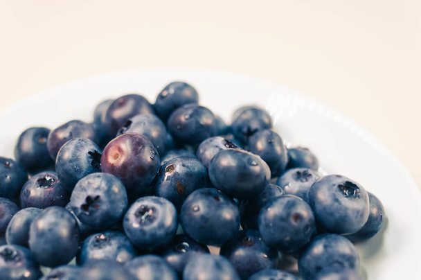 A closeup of a white plate with blueberry. - Fotó, kép