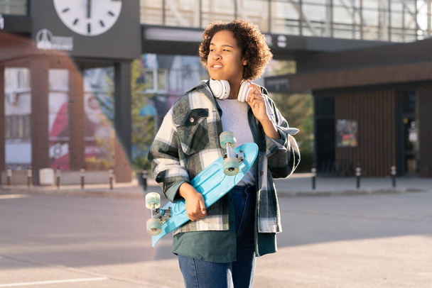 Έφηβη γυναίκα skateboarder με ακουστικά γύρω από το λαιμό - Φωτογραφία, εικόνα