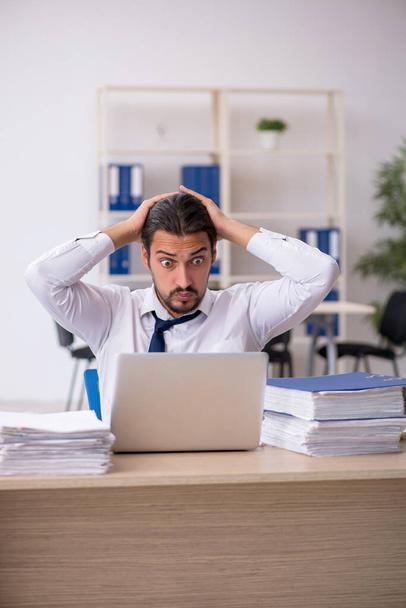 Fiatal férfi alkalmazott elégedetlen a túlzott munka az irodában - Fotó, kép