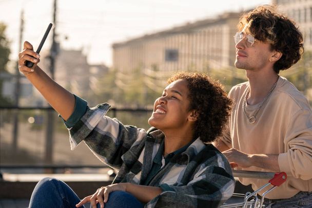Teenage girl with smartphone making selfie with her boyfriend - Фото, изображение