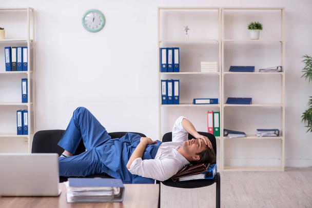 Giovane dipendente di sesso maschile che dorme in ufficio sulle sedie - Foto, immagini