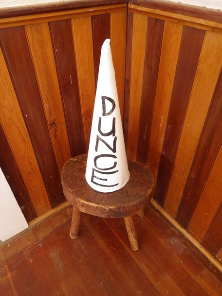 Dunce cap op kruk in hoek van de kamer - Foto, afbeelding