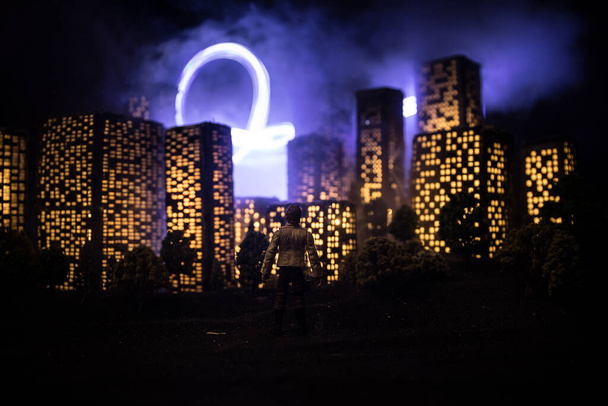 Stadtgebäude im Cartoon-Stil. Realistische Stadtbau-Miniaturen mit Lichtern. Hintergrund. Silhouette eines Mannes, der auf die nächtliche Stadt blickt. Selektiver Fokus - Foto, Bild