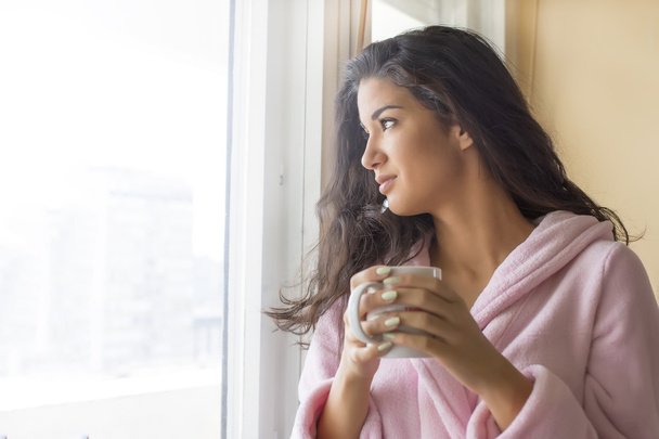 Mujer joven tomando un café por la mañana en la terraza
 - Foto, imagen