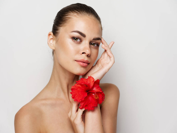 жінка тримає червону квітку в руках макіяж обличчя голі плечі обрізаний вид
 - Фото, зображення
