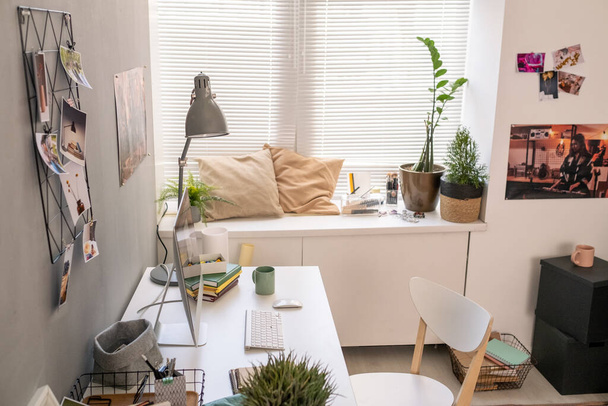 Τμήμα του δωματίου με γραφείο από τοίχο, καρέκλα, δύο μαξιλάρια από το παράθυρο και άλλα πράγματα - Φωτογραφία, εικόνα