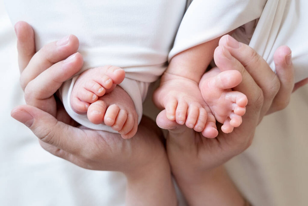 Mama und Papa halten kleine Beine ihrer beiden neugeborenen Zwillingsbabys - Foto, Bild