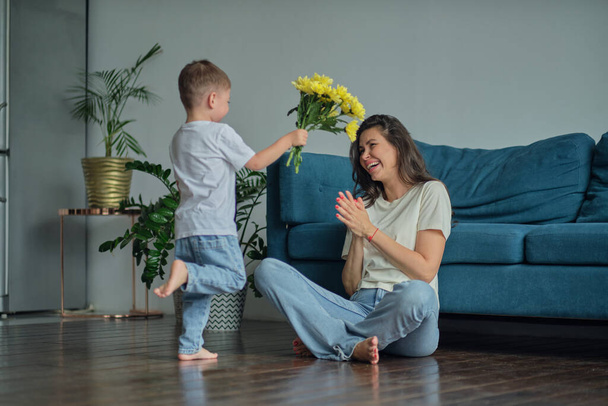 Happy mother day. child son congratulates mother on holiday and gives flowers. congratulating her on mothers day during holiday celebration at home - Foto, Imagen