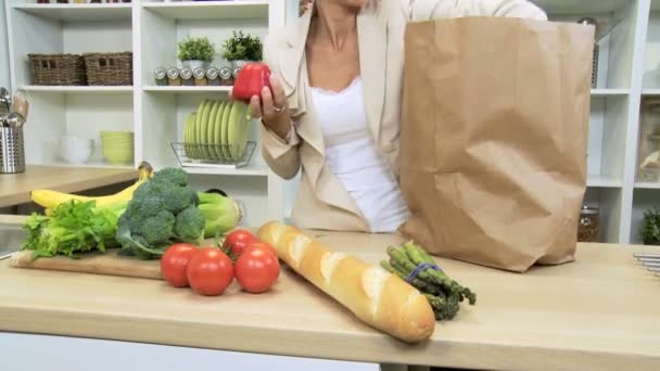 Liikenainen kotona keittiö purkaminen laukku täynnä tuoreita maukkaita orgaanisia
 - Materiaali, video