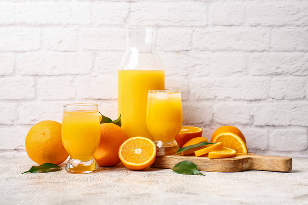 Tasse et verres de jus d'orange savoureux sur fond clair - Photo, image