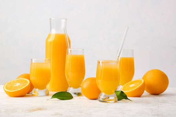 Caraffa e bicchieri di succo d'arancia saporito su sfondo chiaro - Foto, immagini
