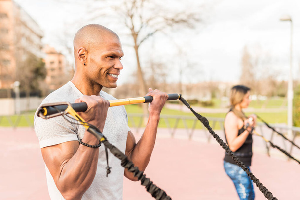 Atlhetic multi-ethnic people exercising with a fitness strap in the park.  - Photo, image
