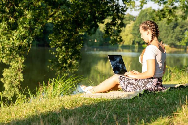 Outdoor online business technology. Student girl work with laptop tablet, computer in nature outside. Person woman sitting in summer park with people. Happy hipster young distance learning concept - Foto, imagen