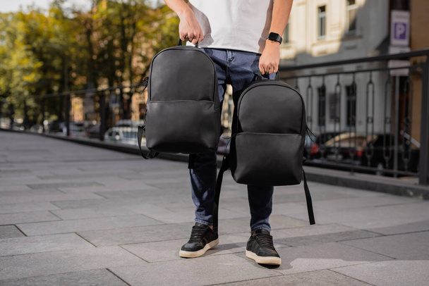 Two black leather backpacks holding male hands in city - Fotoğraf, Görsel