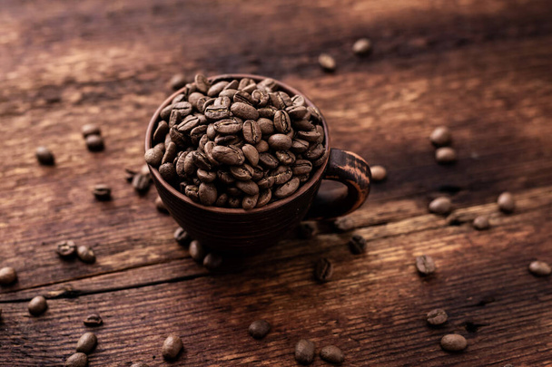 Coffee beans in a clay cup on a brown wooden old background. - Foto, immagini