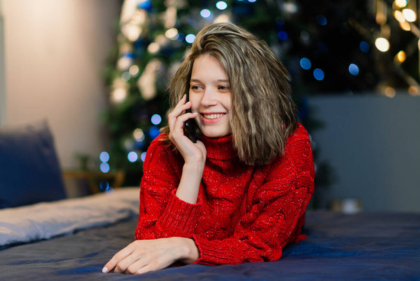 Samimi oturma odasında Noel ağacının yanında mutlu, duygusal bir sürpriz yapan genç kadın, mutluluk kavramı. - Fotoğraf, Görsel