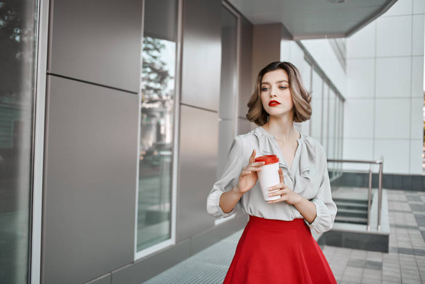 ブロンドの女の子がビルのライフスタイルの近くにコーヒーを飲みながら - 写真・画像