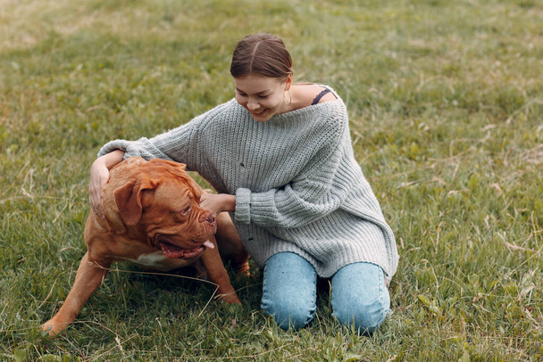 Dogue de Bordeaux or French Mastiff with young woman at outdoor park - Fotó, kép