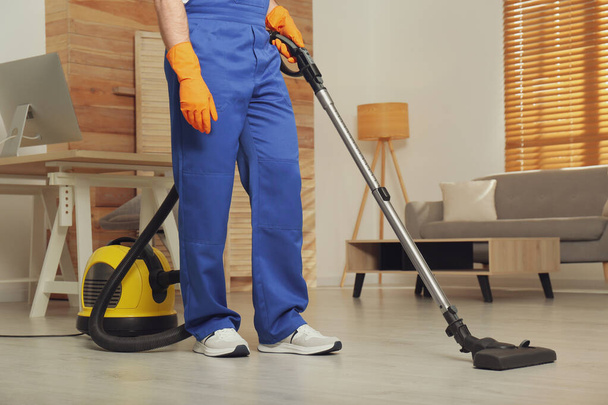 Janitor in uniform vacuuming floor indoors, closeup - Valokuva, kuva