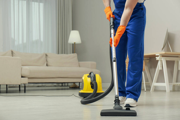Janitor in uniform vacuuming floor indoors, closeup. Space for text - Φωτογραφία, εικόνα