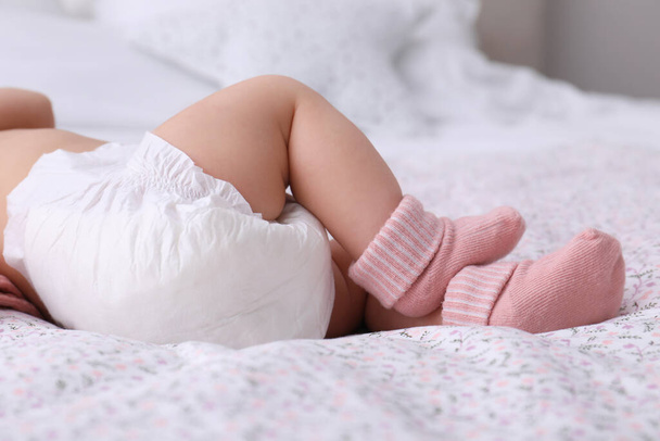 Little baby in diaper on bed, closeup - Foto, Imagem