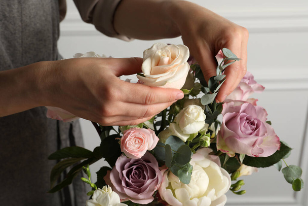 Florist creating beautiful bouquet with roses indoors, closeup - Fotó, kép